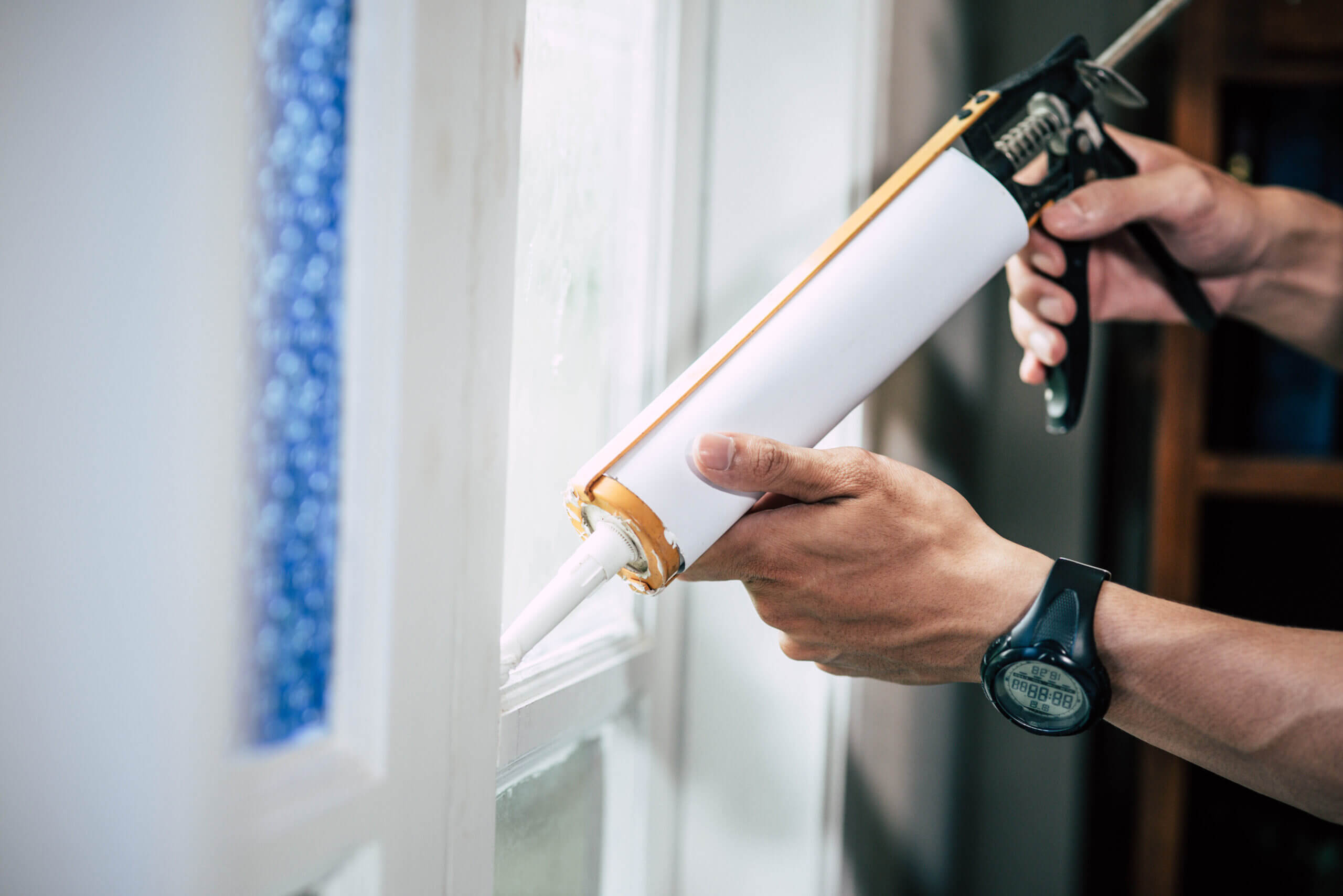 A window installer applying window sealant 