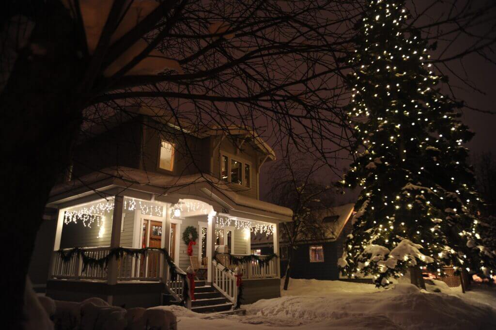 Distant photo of a front porch decorated with icicle lights and other Christmas elements