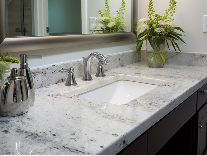 Image of a bathroom vanity with white granite countertops. a white sink, and brushed nickel hardware