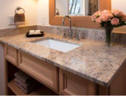 Image of a vanity with light brown granite, a white sink, and brushed nickel hardware