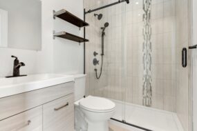 A bathtub shower combo with a sliding glass door in a light colored bathroom