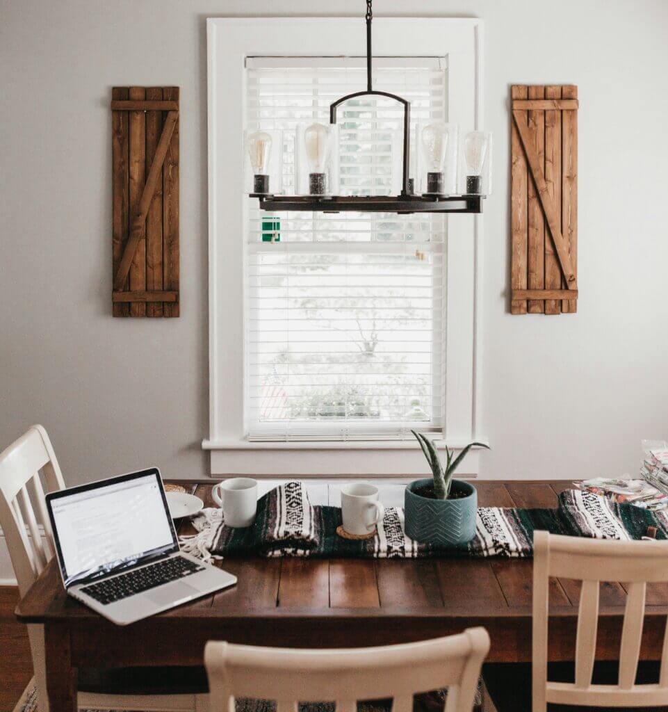 A dining room table with decor in front of a small window