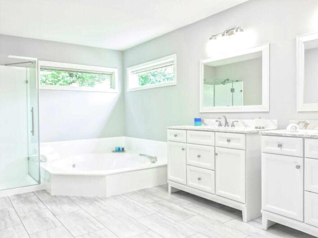 Large white corner tub in an all-white bathroom