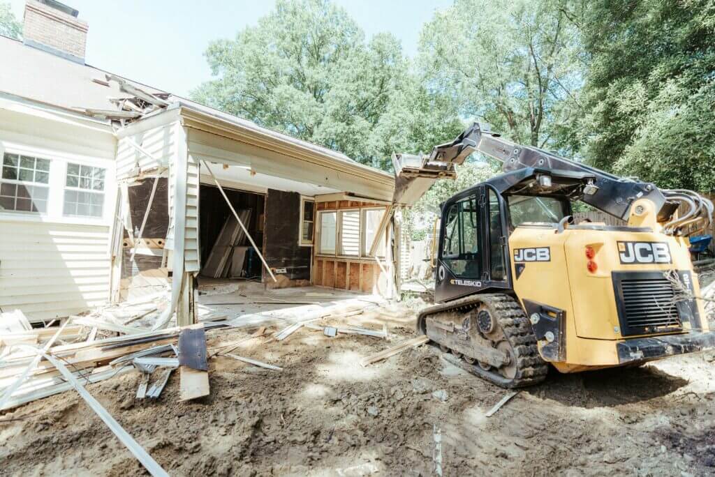 A JCB excavator performs the demo portion of a home remodel