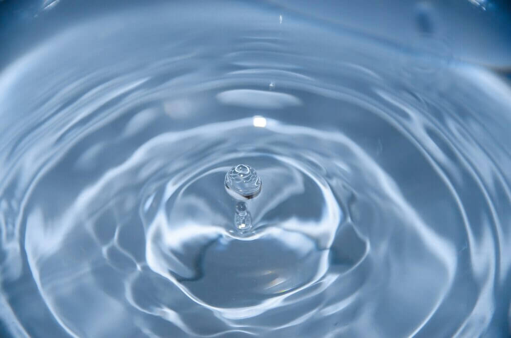 Droplet of clean water into a puddle of clean water