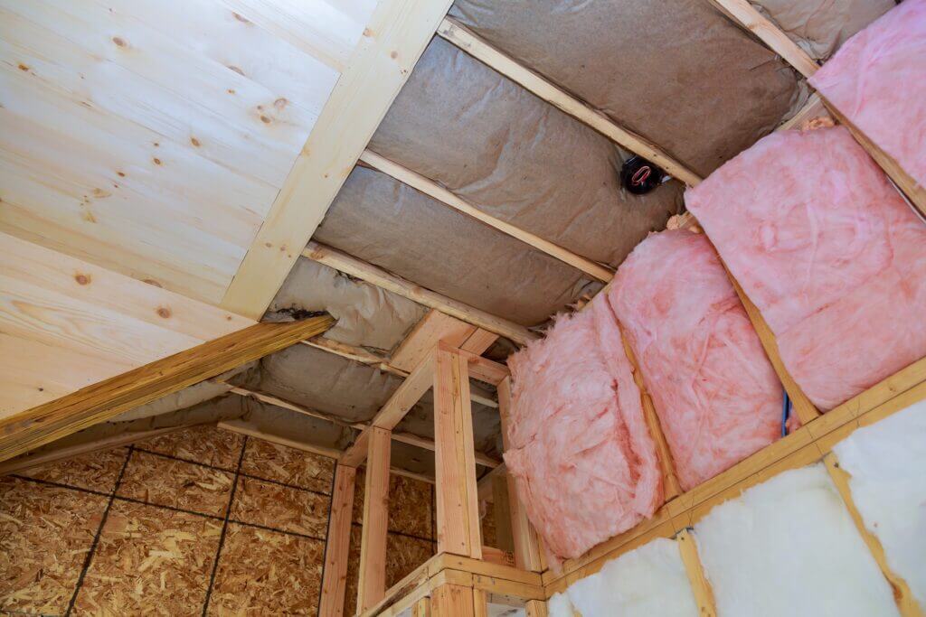 Pink attic insulation partly installed into framing