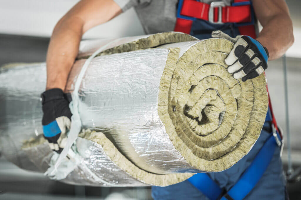 Caucasian Contractor Worker in His 40s with Roll of Mineral Wool Insulation in His Hands Preparing For Commercial Building Walls Insulation.