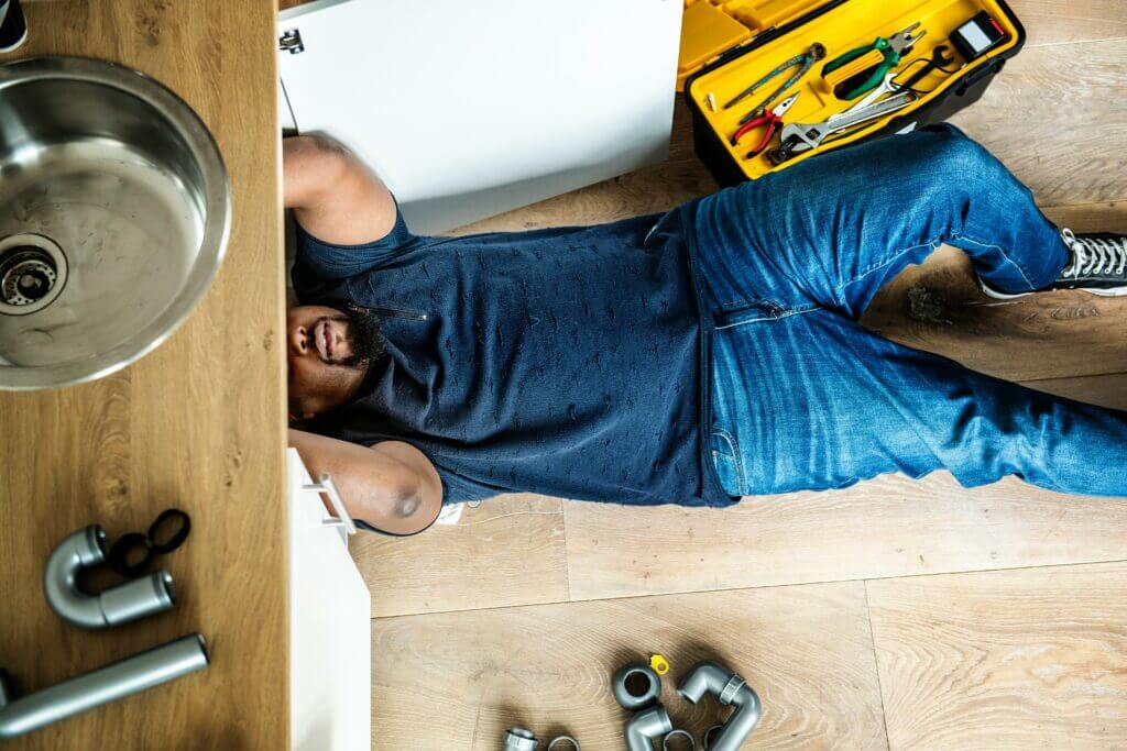 Bird's eye view of a plumber working under the sink