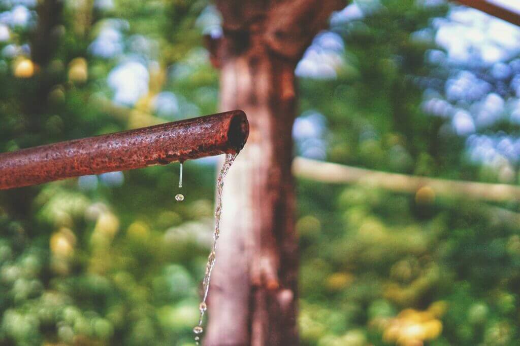 Close up image of a copper pipe dripping outside