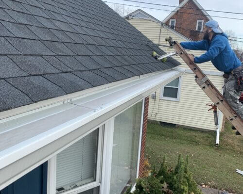 Image from All American Gutter Protection website showing a contractor installing their gutters