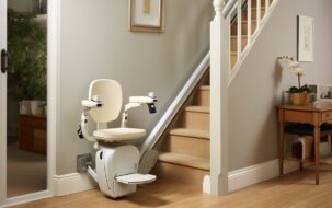 White stairlift installed and docked at the bottom of a straight staircase