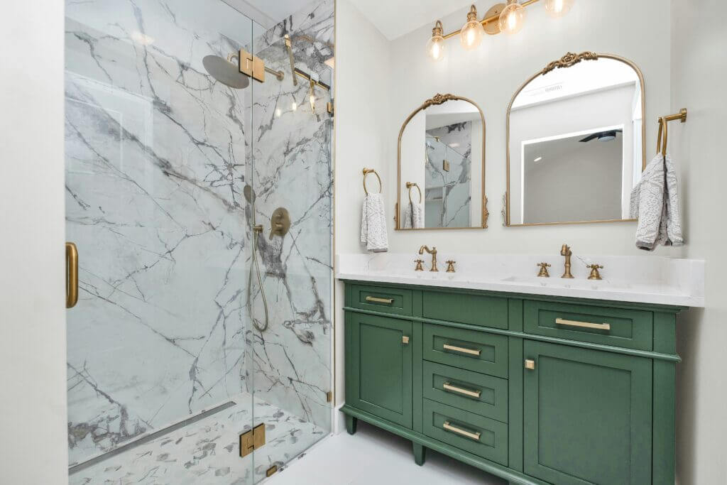 Marble walk-in shower with green vanity and brass accents