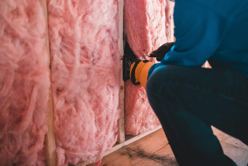 Contractor installing loose-fill fiber insulation in walls