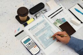 Bird-eye view of a person running calculations at a desk with paperwork and coffee