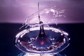 Water droplet against a light and dark purple background