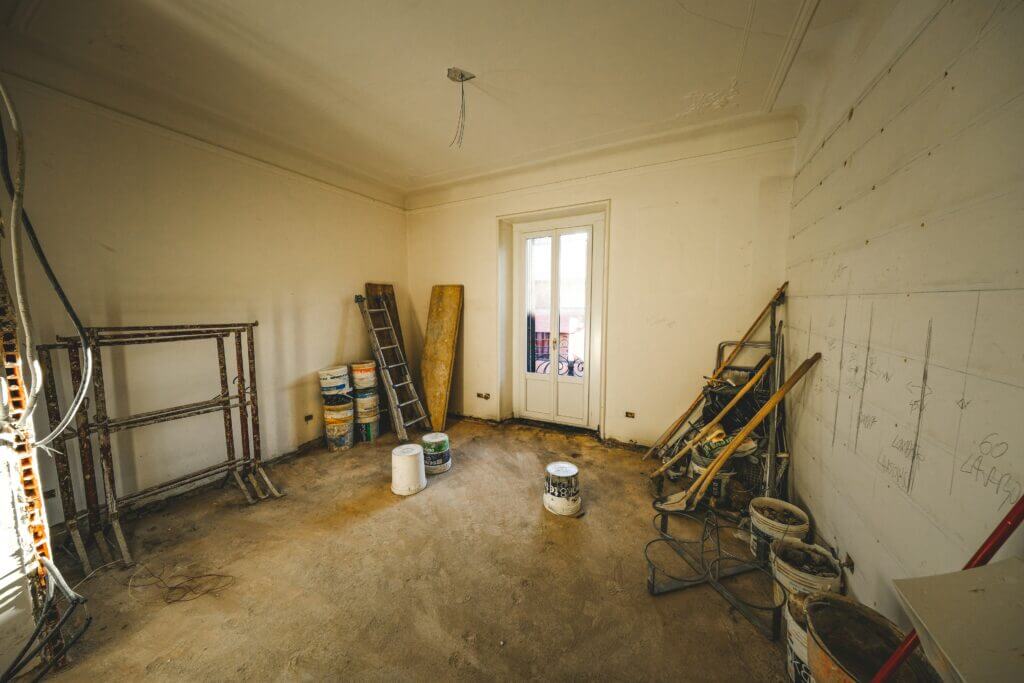 A room shown in the middle of a restoration project with a ladder, paint, and other materials