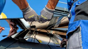 Close-up image of contractors' hands connecting solar panels