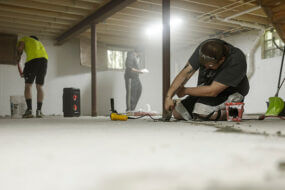 Image shows a crew working on a basement waterproofing project