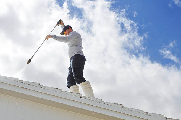 Man pressure washing a roof