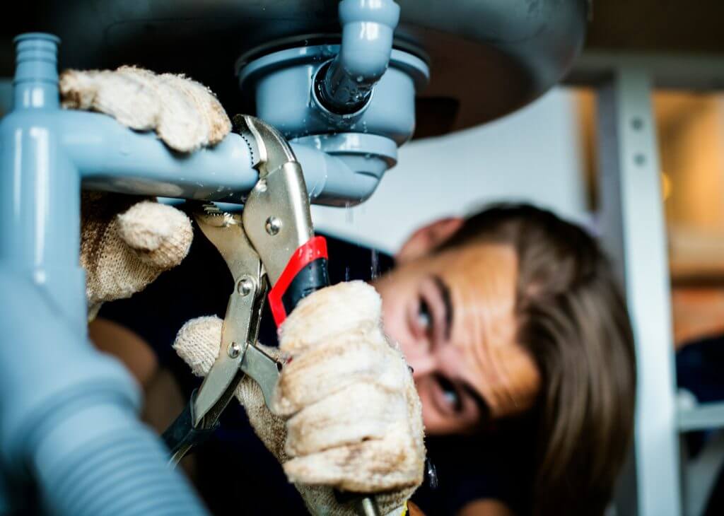 Man with pipe wrench fixing pipe
