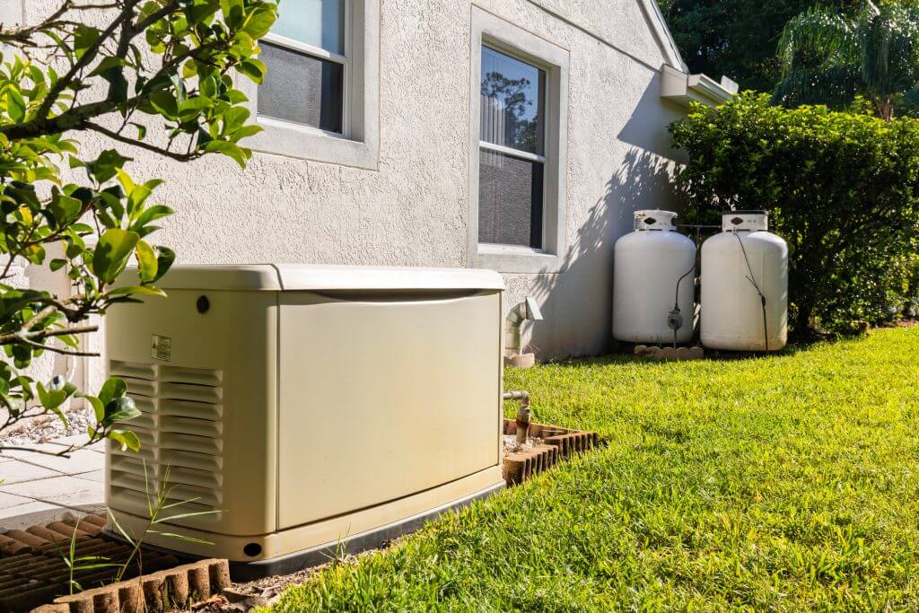 generator and propane tanks in the side yard of a Florida home provide backup emergency electricity during power outage.