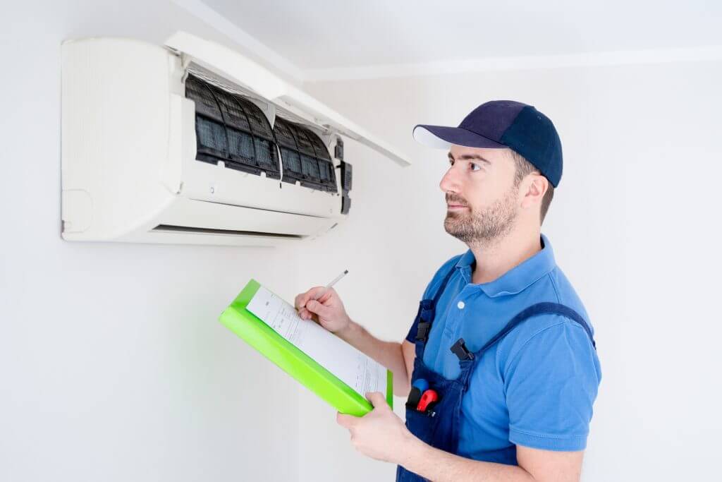Technician with clipboard looking at air conditioner for manual j calculation