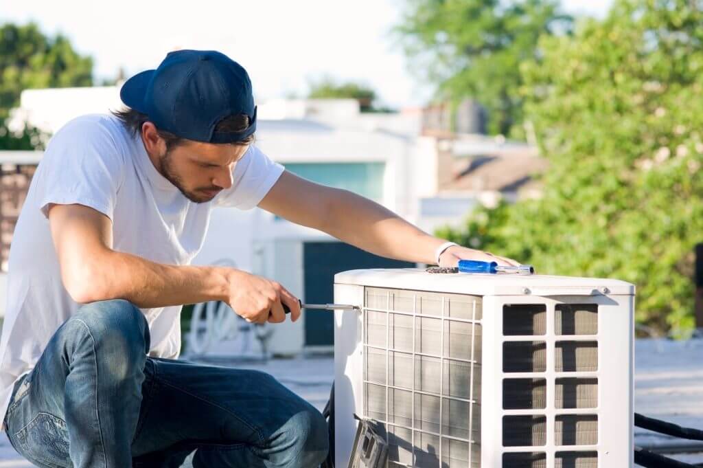Air conditioner technician servicing mini-split heat pump on roof top.