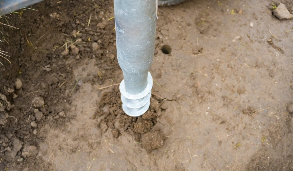 Closeup of iron support on a wooden pillar on the construction site with screw. 