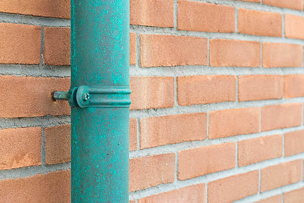 Copper gutter downspout with a green patina