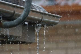 An old gutter with a hole in the bottom, causing it to leak
