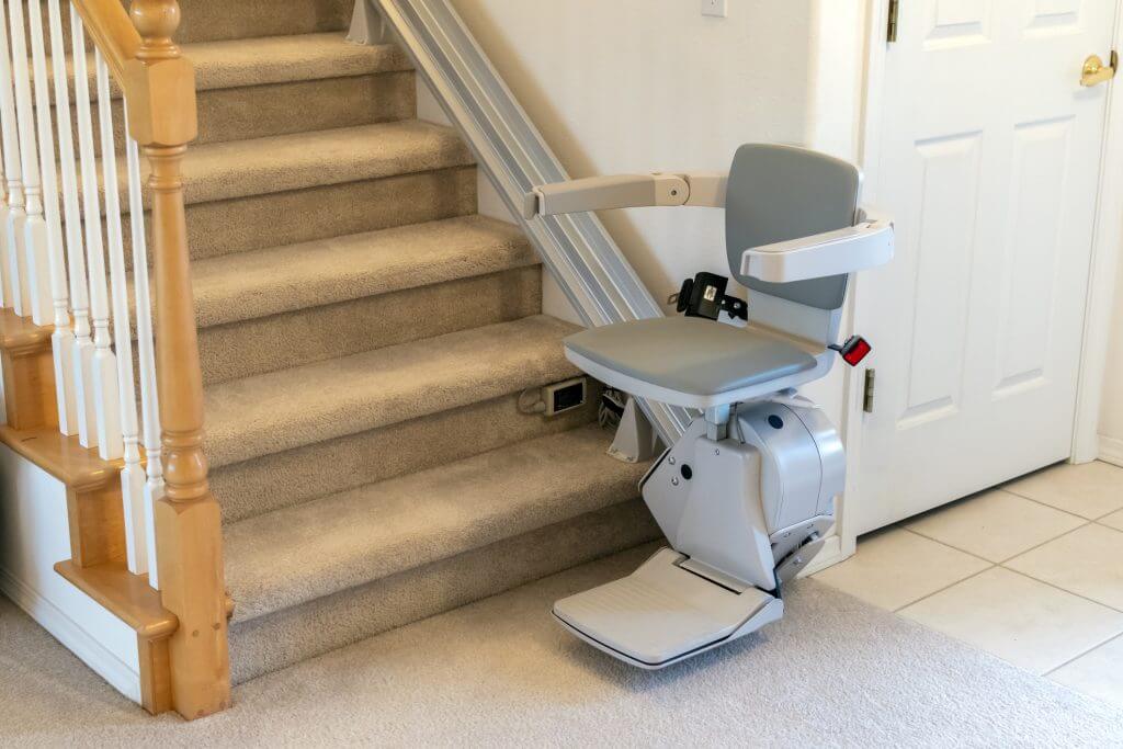 An electric, motorized chair or stairlift on a carpeted staircase in a two story residential home.
