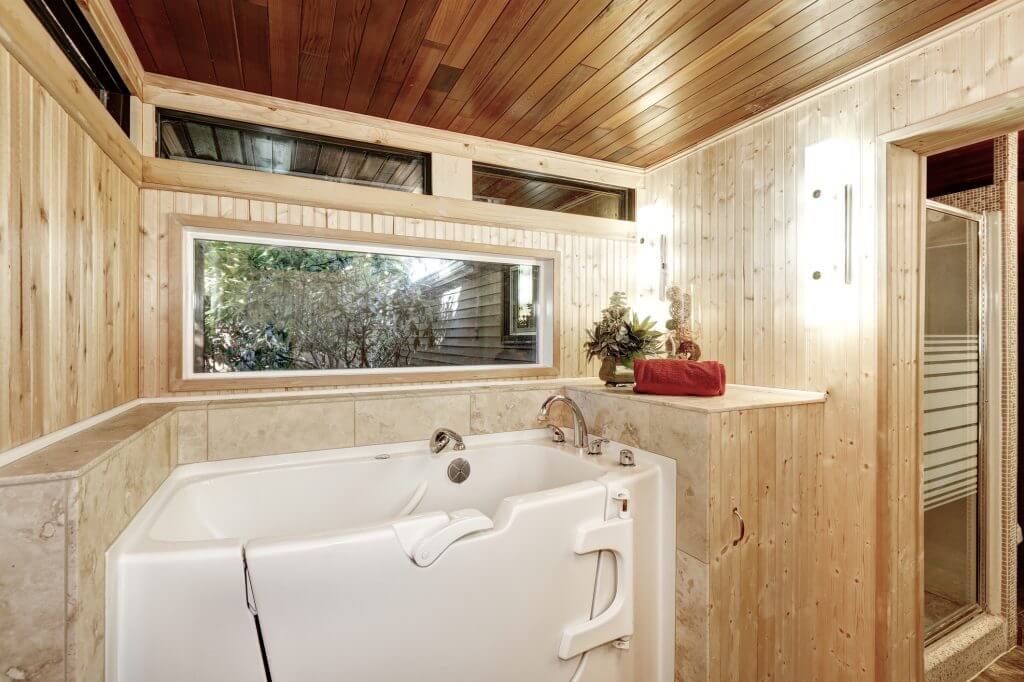 White walk-in tub in wood paneled bathroom