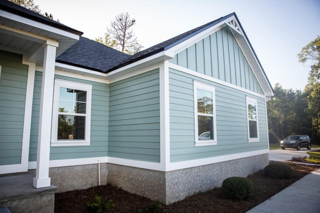Front view of a brand new construction house with blue hardieboard siding, a ranch style home with a yard