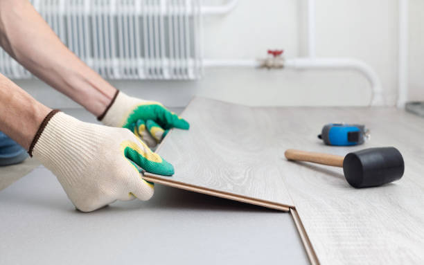 Man in protective gloves lays a gray laminate floor.
