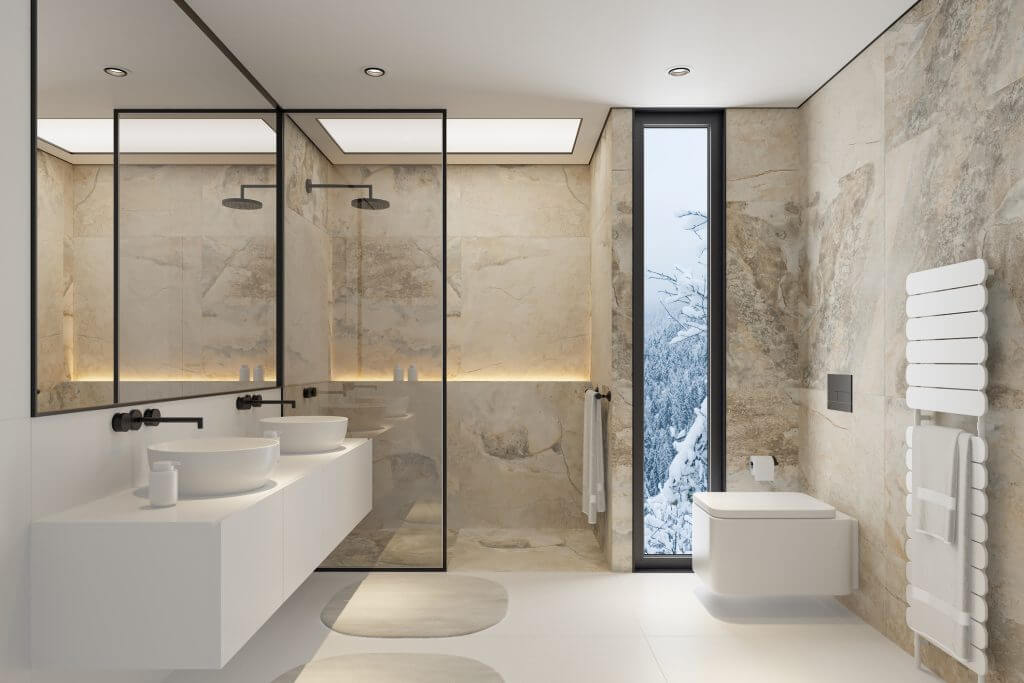 A sleek and sophisticated modern bathroom featuring large limestone or travertine tiles on the walls and floors. The space includes two elegant sinks, a minimalist toilet, and a spacious shower with a contemporary shower head. The expansive mirror enhances the sense of openness, while the natural stone elements provide a serene and luxurious atmosphere. This image is perfect for interior design projects, bathroom renovations, or showcasing high-end bathroom furnishings and fixtures.