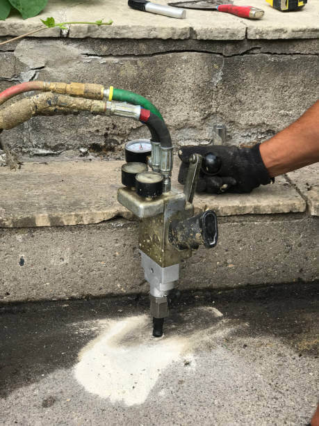 The process of mudjacking or mud jacking. A repair process for sunken or depressed concrete cement sidewalk. An expansion foam is injected under the sunken cement slab through a drilled hole, the high pressure expansion foam lift the cement slab to its original level.