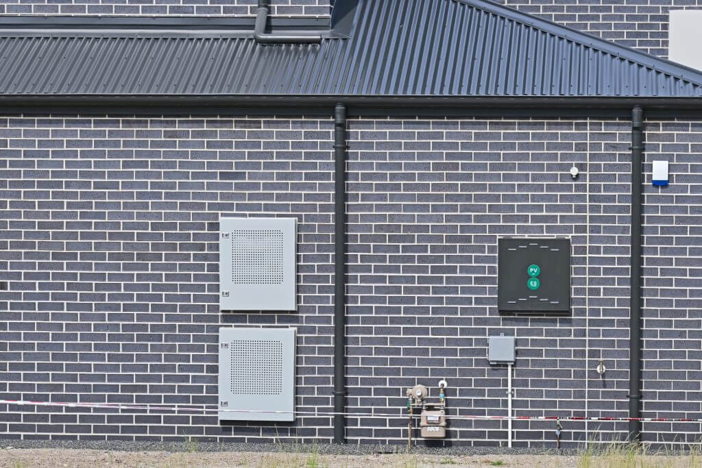 Solar batteries and solar meter box with gas meter and internet connection on the side of a brick house