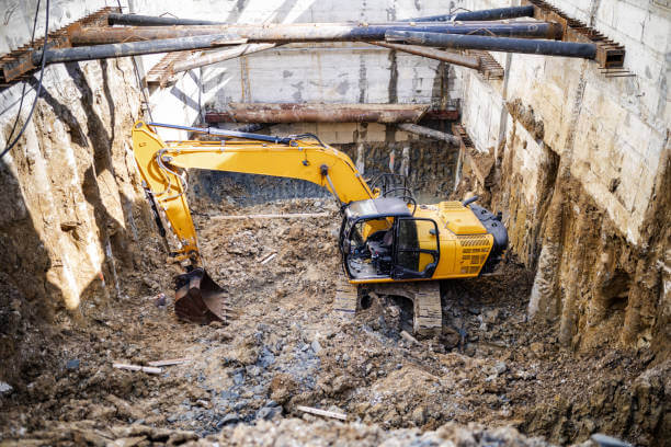 A large excavator is digging into the ground of a construction site